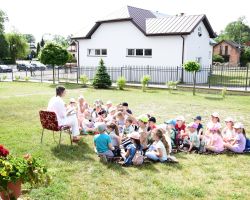 Bibliotekarka czyta dzieciom książkę na zewnątrz