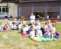 Bibliotekarka czyta dzieciom książkę na zewnątrz