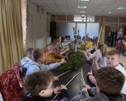 Grupa uczniów siedzi przy stole i robi palmy