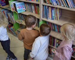 Dzieci oglądają książki w bibliotece.