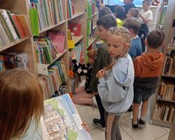 Dzieci oglądają książki na półkach w bibliotece