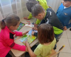Dzieci czytają i oglądają ksiązki przy stoliku.