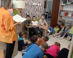 Uczniowie słuchają lektury, którą czyta im bibliotekarka.