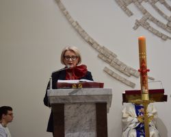Kobieta stoi przy mównicy w kosciele i czyta