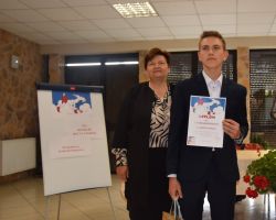 Uczeń stoi obok kobiety i trzyma w ręku dyplom.