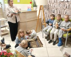 Pani bibliotekarka czyta dzieciom książkę w bibliotece.