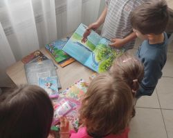 Dzieci oglądają ksiązki przy stoliku w bibliotece.
