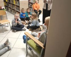 Pani bibliotekarka czyta dzieciom książkę w bibliotece.
