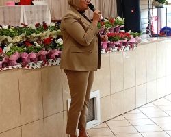 Kobieta stoi na sali i przemawia przez mikrofon