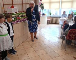 Kobieta przemawia przez mikrofon do zgromadzonych gości.