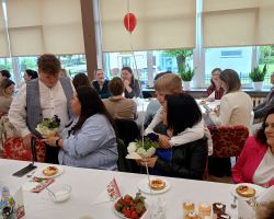 Dzieci podchodzą do rodziców, składają życzenia i wręczają kwiaty.