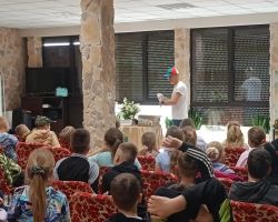 Uczniowie siedzą na krzesłach na sali widowiskowej.