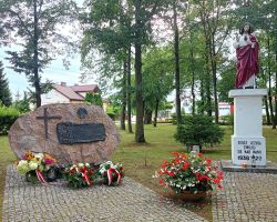Zdjęcie wiązanek i zniczy przy pomniku poległych w czasie wojny