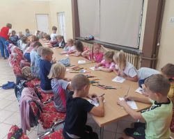 Przedszkolaki kolorują obrazki na kartkach