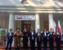 Uczniowie czytają poezje Kochanowskiego przy budynku Urzędu Gminy