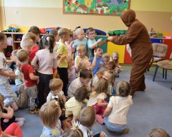 Bibliotekarka przebrana za misia pokazuje dzieciom książkę w przedszkolu