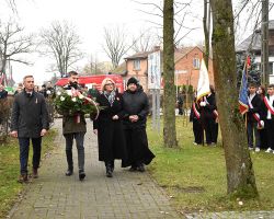 Złożenie kwiatów pod pomnikiem przez władze gminy i proboszcza