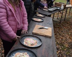 Dzieci stoją przy stole gdzie robią podpłomyki-małe pizze.