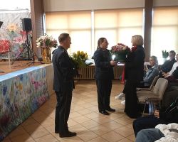 Na zdjęciu panowie składają życzenia i wręczają kwiaty pani Wójt