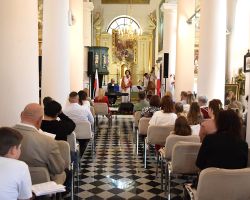 Ludzie siedzą w kościele i słuchają koncertu pieśni patriotycznych