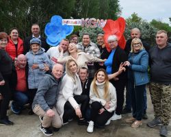 Grupa ludzi pozuje do zdjęcia przy ściance dekoracyjnej