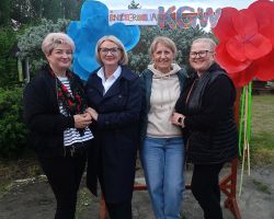 Cztery kobiety pozują do zdjęcia przy ściance dekoracyjnej
