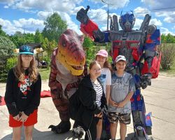 Dzieci pozują do zdjęcia z dinozaurem i transformersem