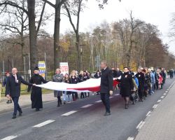 zdjęcie przedstawia osoby niosące flagę Polski
