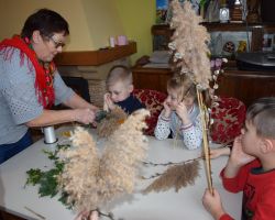 Zdjęcie przedstawia dzieci robiące palmy wielkanocne