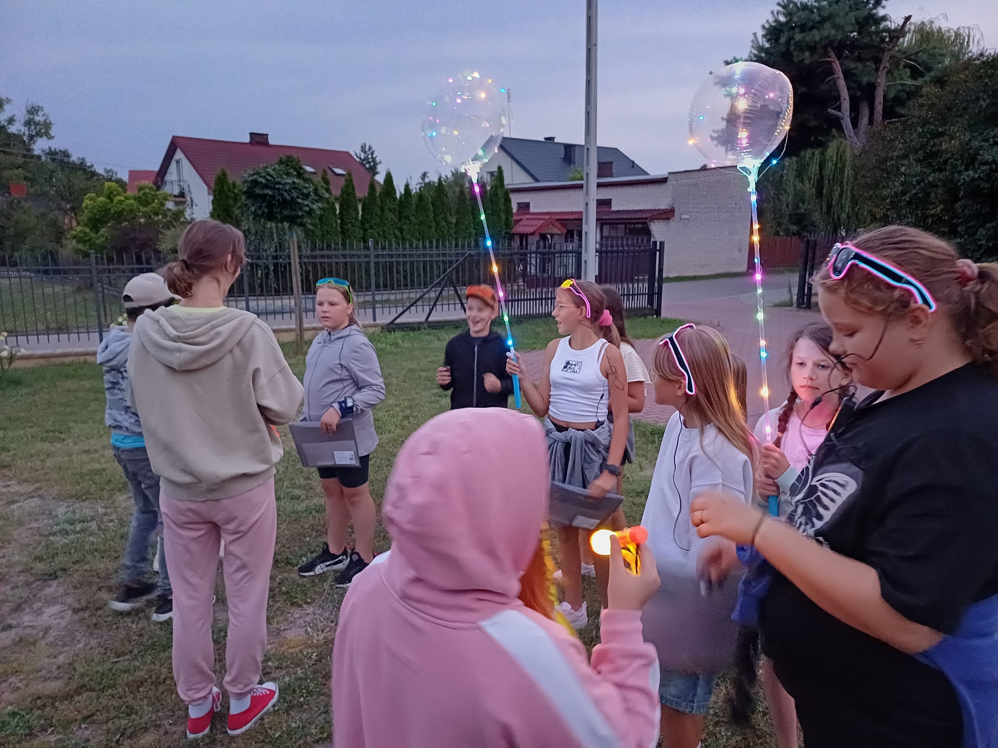 Zdjęcie przedstawia dzieci z fluo gadżetami