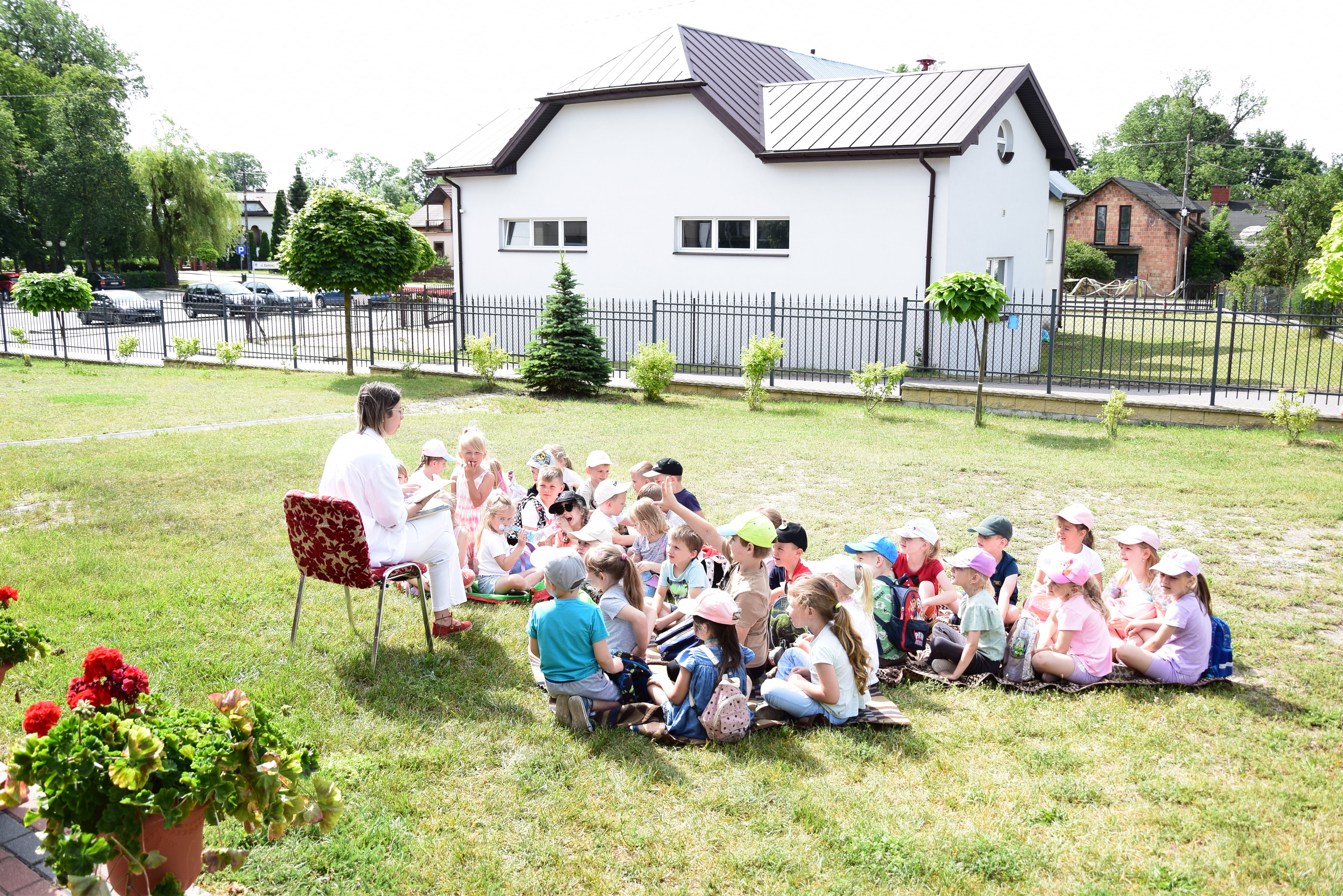 Dzieci na kocach słuchają bajek czytanych przez bibliotekarkę.