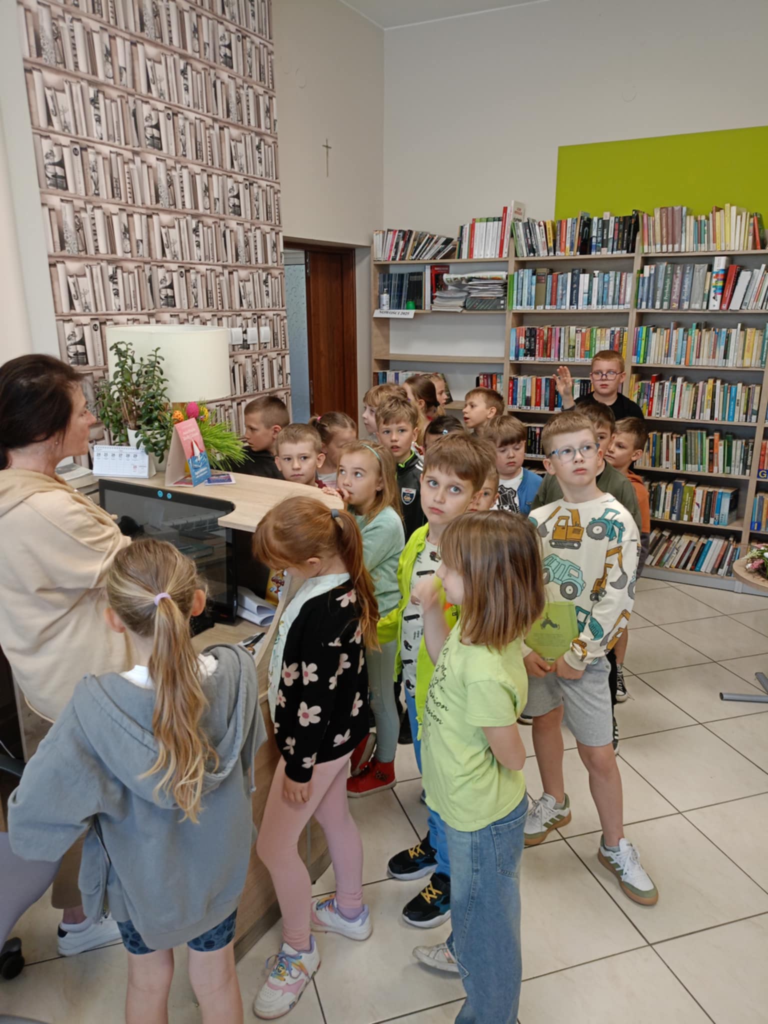 Uczniowie słuchają bibliotekarki w bibliotece