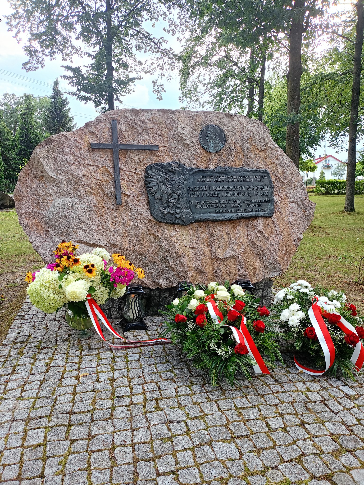 Zdjęcie wiązanek i zniczy przy pomniku polgłych bohaterów w czasie wojny