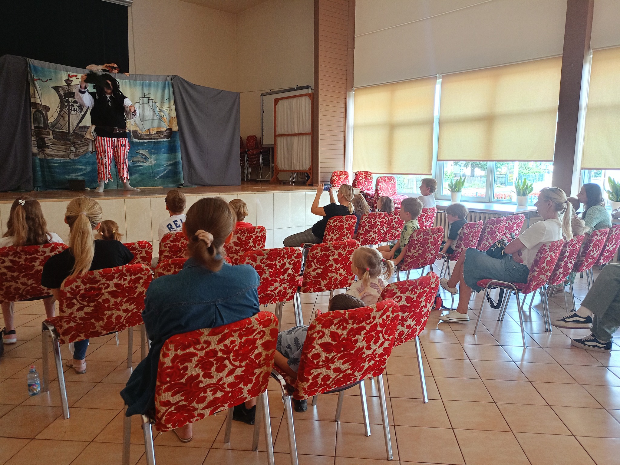 Zdjęcia przedstawia dzieci na sali oglądające teatrzyk