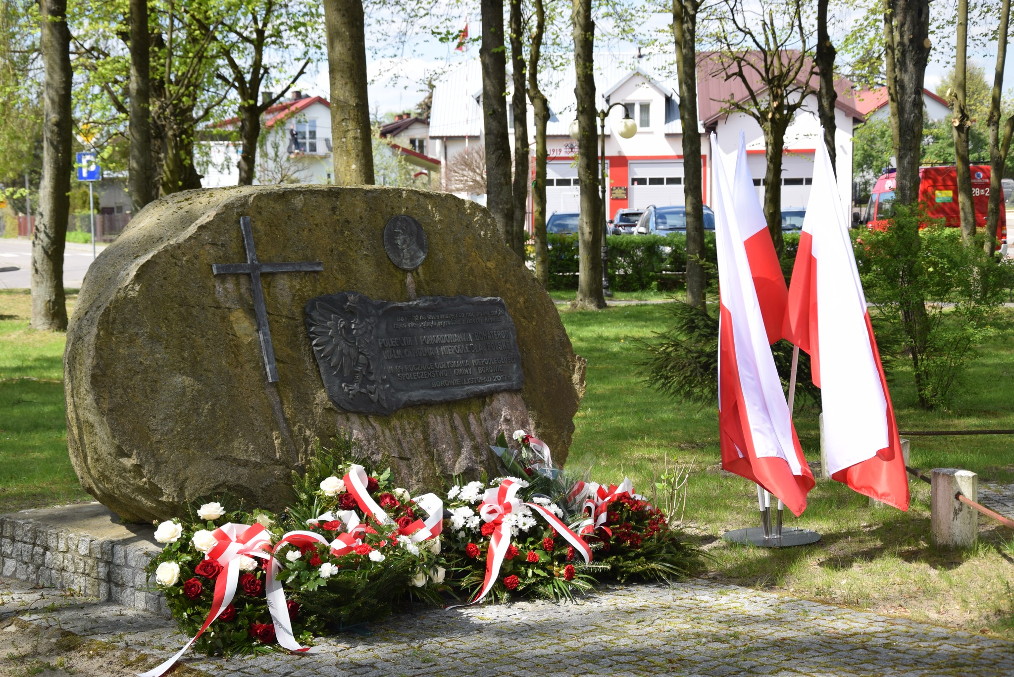 zdjęcie przedstawia kwiaty złożone pod Pomnikiem Niepodległości