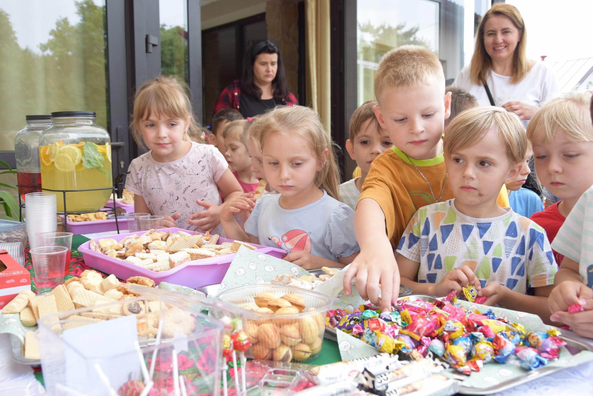 Zdjęcie przedstawia dzieci jedzące słodkości przygotowane przez panie z KGW